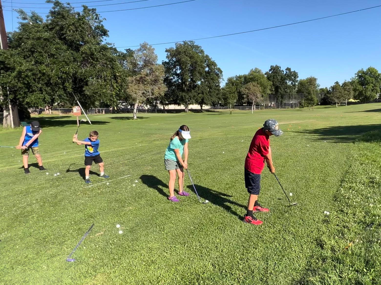 junior golfers lined up on driving range